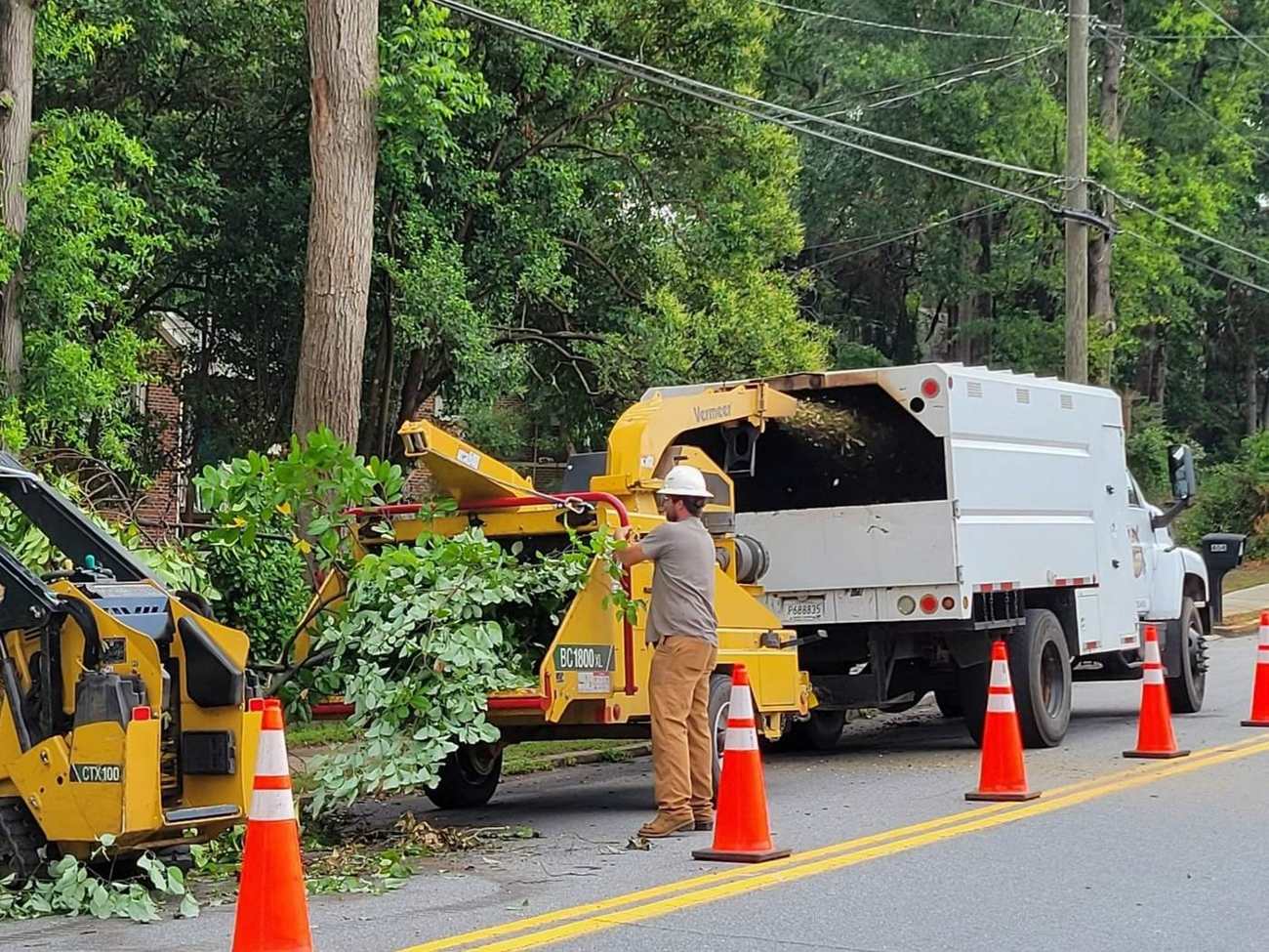 Mullinax crew feeding limbs into the chipper beside the chip truck on a residential street in Central, SC